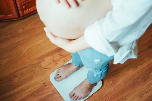 Image of woman weighing herself and experiencing weight gain through pregnancy Merry Hill